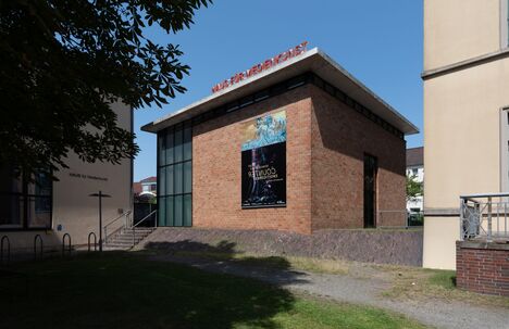 Eine Frontalansicht des Hauses für Medienkunst in Oldenburg. Das Haus ist ein Flachdach mit rotem Klinker und einer großen Glasfront an der linken Seite.