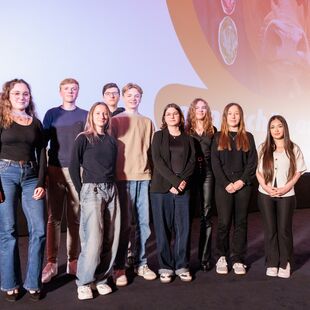 Neun Schüler*innen stehen auf der Bühne des Astor Kinos in Hannover und blicken in die Kamera.