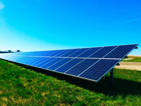 Ein großes Solarpaneel auf einer grünen Wiese im hellen Sonnenlicht.